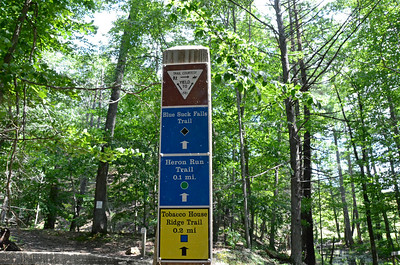 Photograph of vertical set of hiking trails signs that provide symbols and text with details of trail use, trail names, and lengths